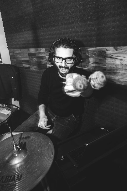 Drummer laughing behind the cymbals in the rehearsal room, black and white