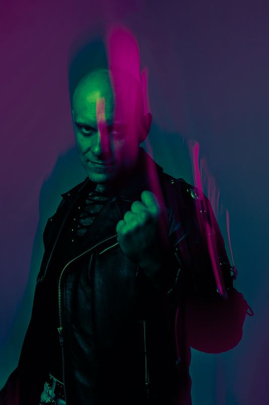 Ritratto in studio di un uomo in giacca di pelle, luce divisa magenta e verde