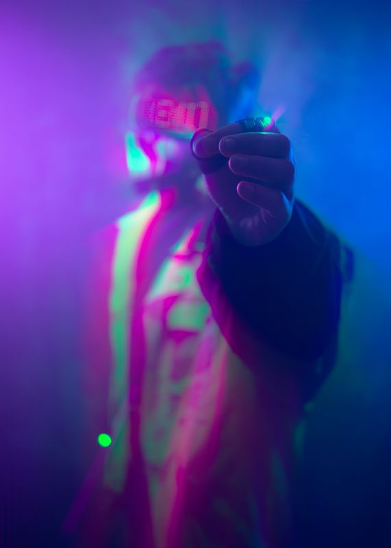 Figura illuminata di magenta e verde con la mano tesa verso l'obiettivo