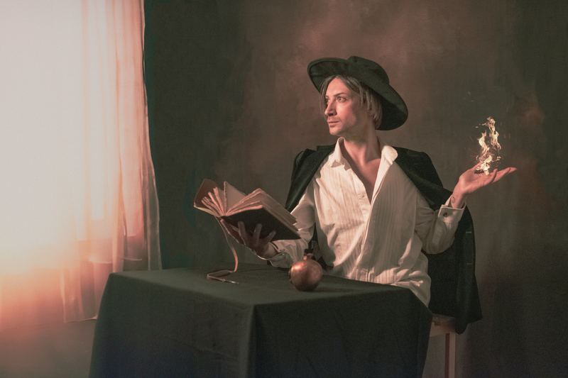 Ritratto pittorico: costume rinascimentale, libro e oggetti di scena sul tavolo